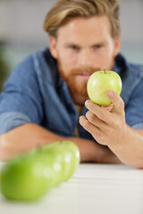 picture of man looking at a green apple