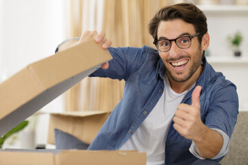 happy man opening parcel box at home showing thumb up