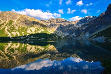 Beautiful summer mountain landscape by the lake. View of the mountains reflecting in the water at...
