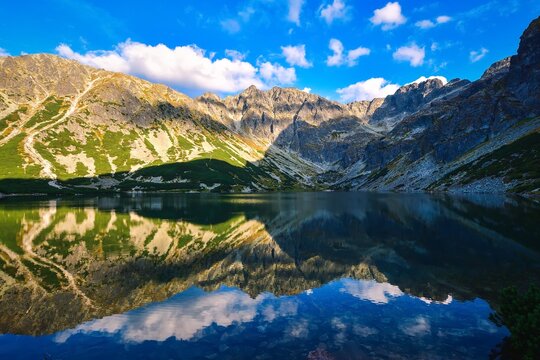 Beautiful summer mountain landscape by the lake. View of the mountains reflecting in the water at Czarny Staw Gasienicowy in the Polish High Tatras. © shadowmoon30