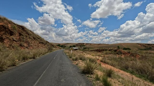 Car crosses a bridge on a bumpy road from Antsirabe to Miandrivazo in Madagascar, Central Madagascar landscape with blue sky.