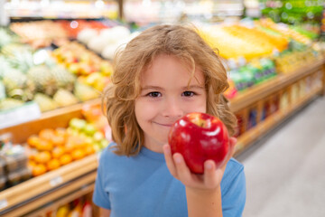 Portrait of child with shopping cart full of fresh vegetables in a food store. Supermarket shopping and grocery shop concept. Shopping kids. Child buying grocery in supermarket. hold shopping basket. - obrazy, fototapety, plakaty