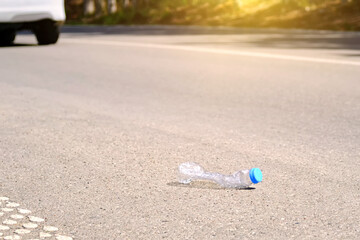 An empty plastic water bottle was thrown onto a country road against the backdrop of a passing car.