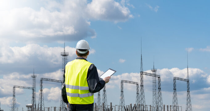 Worker with digital tablet on a background of power station - Powered by Adobe