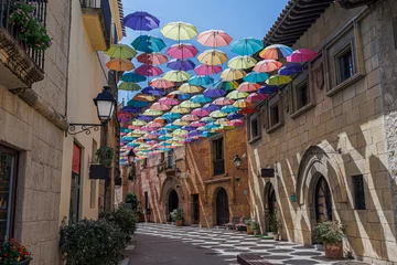 Fototapeten Umbrellas Suspended and Joined with Each other in a Street of Poble Espanyol to Form a Roof of Colorful Umbrellas, Barcelona, Spain © GioRez