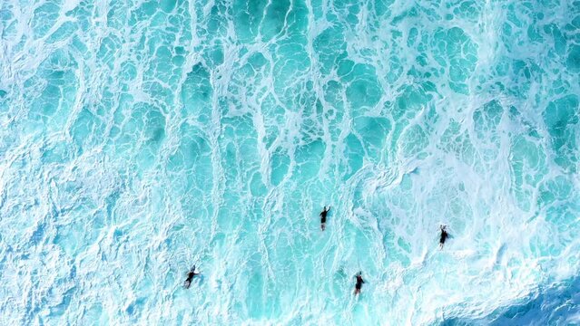 Aerial Top Forward Shot Of Male Surfers Swimming With Surfboards In Foamy Sea During Vacation - Oahu, Hawaii