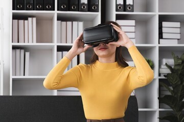 Happy pretty young woman in VR glasses sitting in sofa at home.