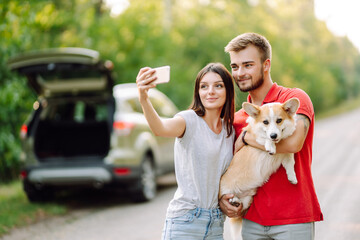 Selfie time. Young couple together with their beloved pet on a walk doing selfie.The concept of an active lifestyle, travel, love and vacation. Pet and human.