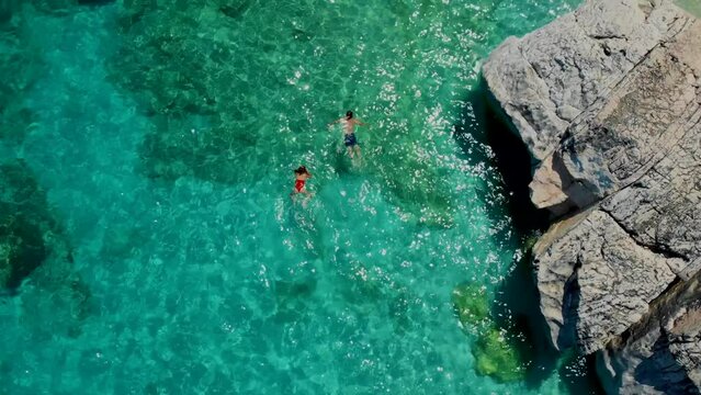 Men and women on the beach in Sardinia Italy, couple men and women playing in the ocean with crystal clear blue water snorkeling at Cala Luna Sardinia Italy Golfo Di Orosei during summer