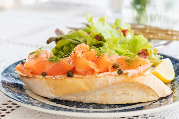 Smoked salmon with cream cheese on french baguette and fresh salad. 