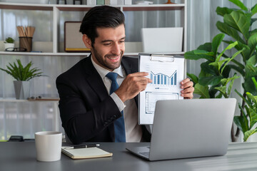 Professional businessman in black suit, present financial data or BI paper via laptop during online meeting. Remote work concept with virtual meeting presentation of effectiveness remote work. Fervent