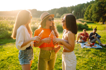 Happy groop of friend resting in nature in the picnic drinking beer, cheers. People, lifestyle, relaxation and vacations concept.