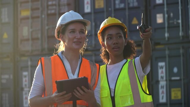 group of two diversity woman container worker working together with tablet computer  in  warehouse logistic in Cargo . cooperation of african american woman and Caucasian female.