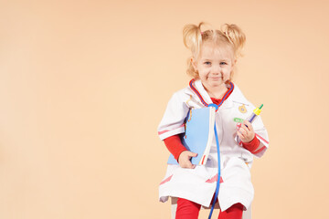 A little girl with a stethoscope holds a book in her hands and looks into it.