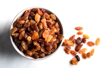 Dried raisins in bowl on marble background. Top view. Close-up.