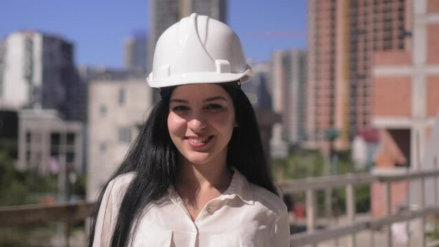 Middle-aged female architect wearing helmet on construction site while working, she smiles at camera and smiles. Successful and proud inspector. Portrait of Female Engineer. Construction Manager