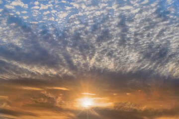Fototapeta premium Summer evening sky in the picturesque clouds, lit by the rays of the setting sun.