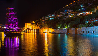 Fototapeta na wymiar A pirate tourist ship at anchor near ancient shipyard at night - Alanya, Turkey