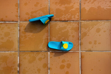 Pool flip-flops lying on the ground with splashes of water from a swimming pool. Summer concept.