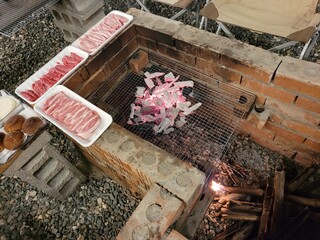 sausages being grilled on the coals in the brazier