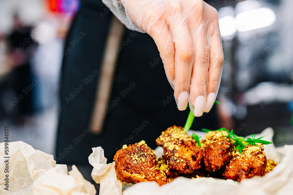 Wall mural woman chef cooking chicken wings in a sauce in the kitchen