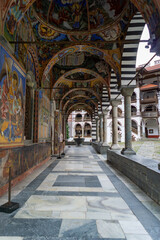 Fototapeta na wymiar Cloister of the Rila Monastery in Bulgaria, it has many arches and columns, many paintings and frescoes, it is very colorful, photo on a cloudy day.