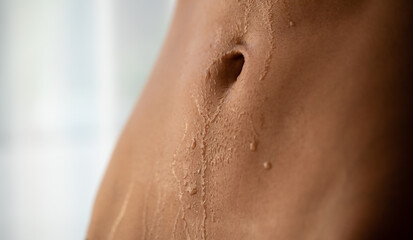 Close up of a toned female torso with sweat on the skin after a workout. Woman with perfect abdominal muscles