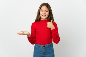 Little girl over isolated white background holding copyspace imaginary on the palm to insert an ad and with thumbs up