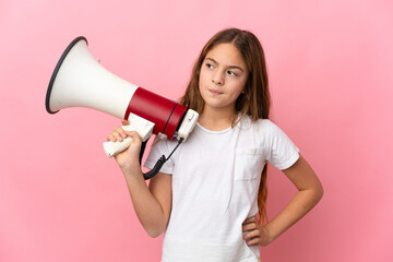 Child over isolated pink background holding a megaphone and thinking