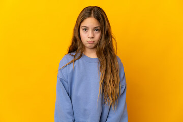 Child over isolated yellow background with sad expression