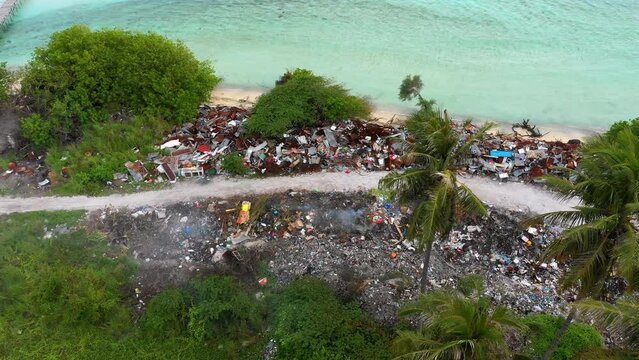Aerial: Drone Forward Tilt Down Shot Of Garbage Burning On Landscape By Sea - Oahu, Hawaii