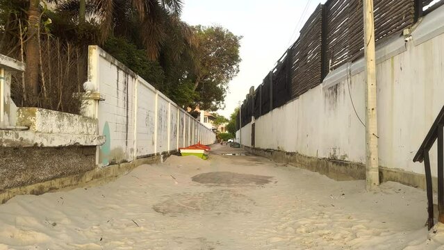 Alleyway with sand on ground and people walking in distance