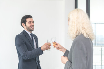 Businessman and businesswoman drinking champagne to celebrate success of investment agreement after meeting, teamwork and partnership concept.