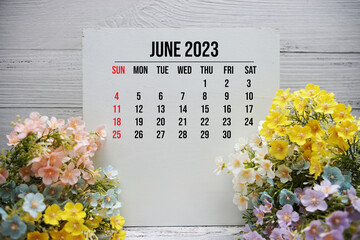 June 2023 monthly calendar on easel stand on wooden background