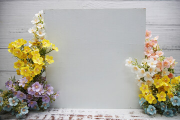 Empty white borad with flowers decoration on wooden background