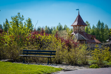 A wooden tower in a grove between trees by a bench.