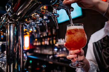 woman bartender hand at beer tap pouring a draught beer in glass serving in a restaurant or pub