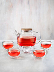 Glass Teapot and cups with red tea on white background