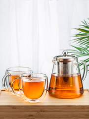 Asian tea concept, two glass cups of tea and teapot, space for a text on white background. Brewing and Drinking tea.