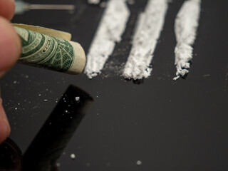 Syringe for injection and cocaine powder, on a black background. Drugs and money.