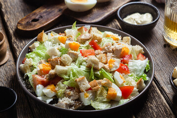 Salad of iceberg leaves, chicken, eggs and tomatoes in a plate. Caesar salad