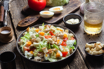 Salad of iceberg leaves, chicken, eggs and tomatoes in a plate. Caesar salad