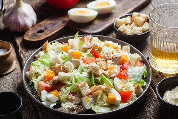 Salad of iceberg leaves, chicken, eggs and tomatoes in a plate. Caesar salad