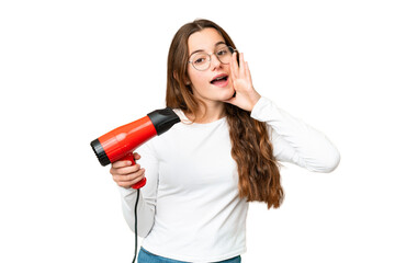 Teenager girl holding a hairdryer over isolated chroma key background shouting with mouth wide open