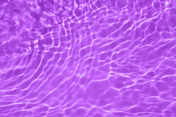 Purple water with ripples on the surface. Defocus blurred transparent blue colored clear calm water surface texture with splashes and bubbles. Water waves with shining pattern texture background.