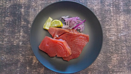 bluefin tuna fresh- ready to prepare - on a dark background and black plate
