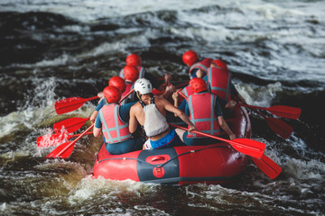 Red raft boat during whitewater rafting extreme water sports on water rapids, kayaking and canoeing on the river, water sports team with a big splash of water - obrazy, fototapety, plakaty