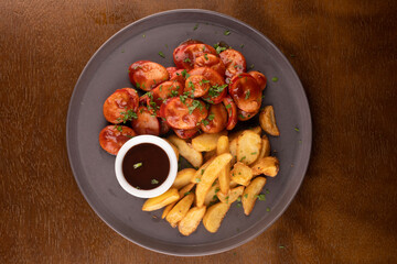portion of bock sausages with rustic fries and barbecue sauce and curry with green onions top view