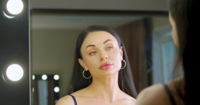 Zoom in of a young Caucasian woman applying makeup foundation in fromt of mirror at home.
