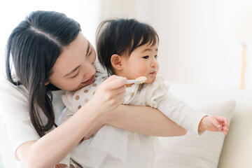 赤ちゃんに離乳食を食べさせるママ